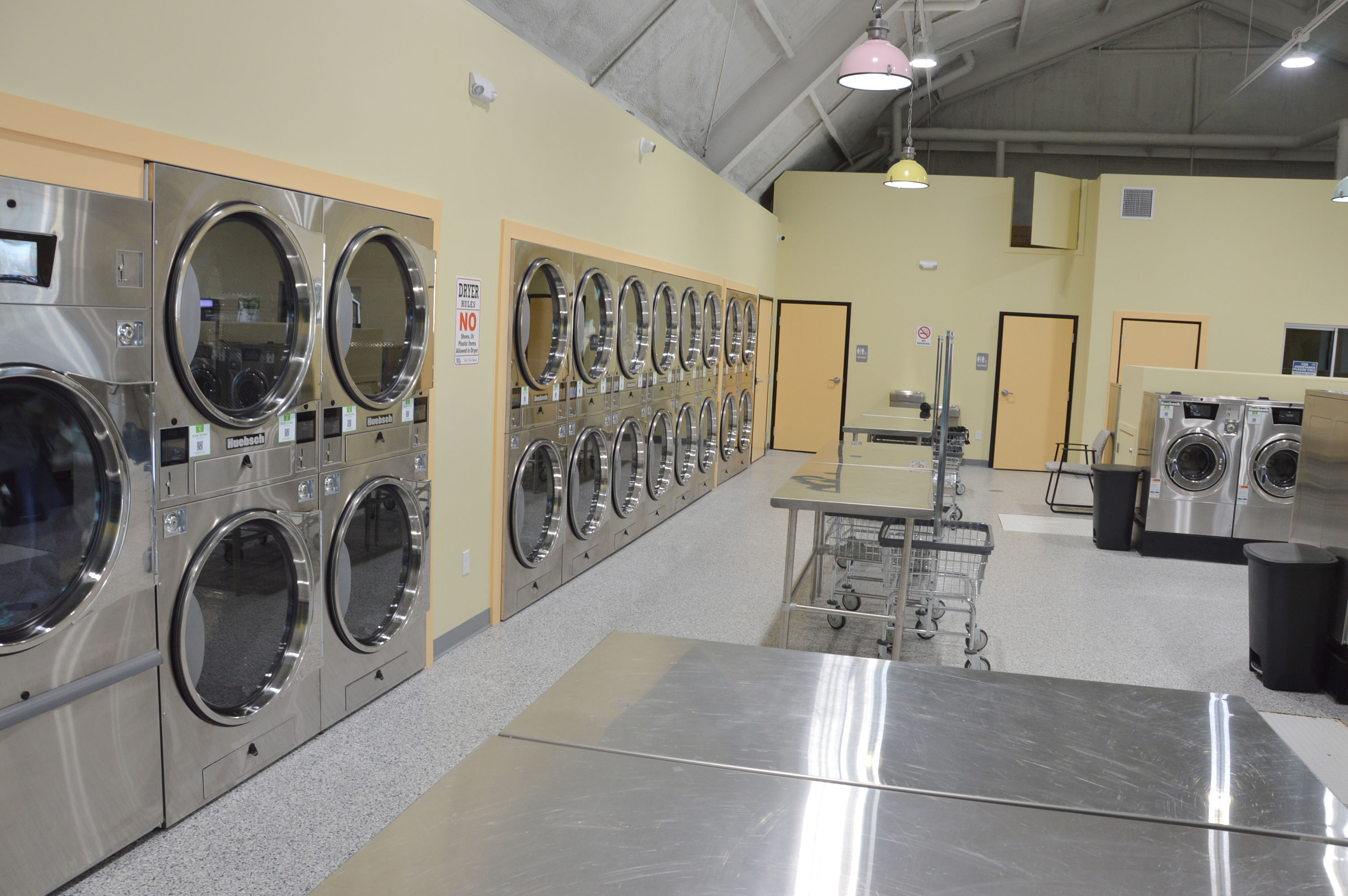 Interior view facing north with dryer wall, folding tables, and washer area